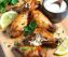 Golden crispy air fryer chicken wings with lemon and parsley on wooden board, juicy inside, no oil added