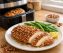 Golden pecan crusted chicken breast with crispy nut coating on white plate, served with green beans and lemon, air fryer in background